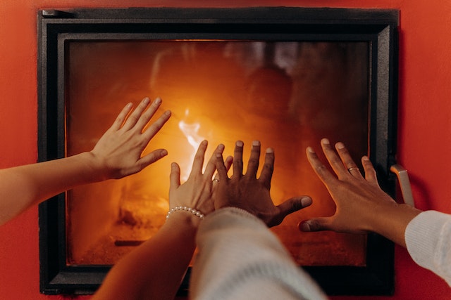 hands hovering over a fireplace